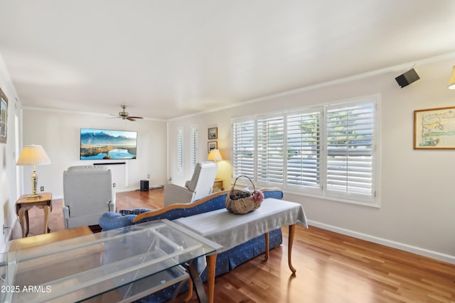 living room featuring wood-type flooring, ceiling fan, and ornamental molding