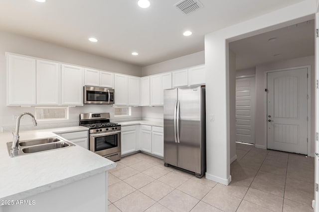 kitchen featuring sink, appliances with stainless steel finishes, white cabinets, and light tile patterned floors