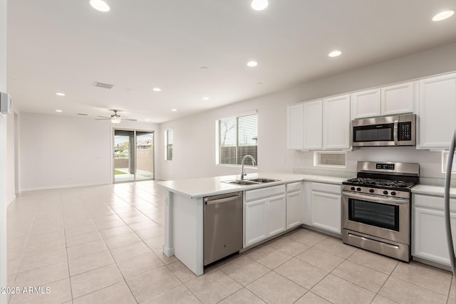 kitchen with white cabinetry, kitchen peninsula, a wealth of natural light, sink, and appliances with stainless steel finishes