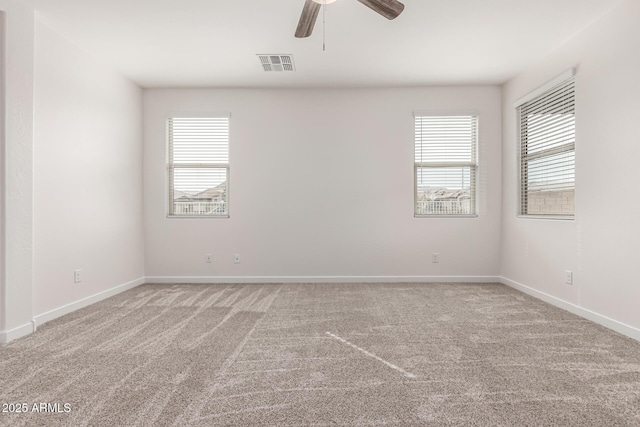 carpeted spare room featuring ceiling fan and plenty of natural light