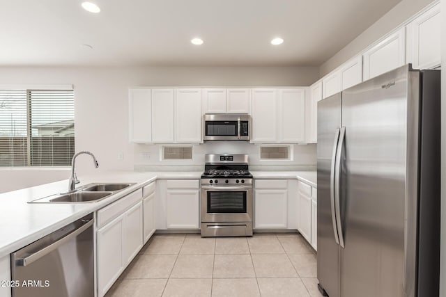 kitchen with light tile patterned flooring, white cabinetry, stainless steel appliances, and sink