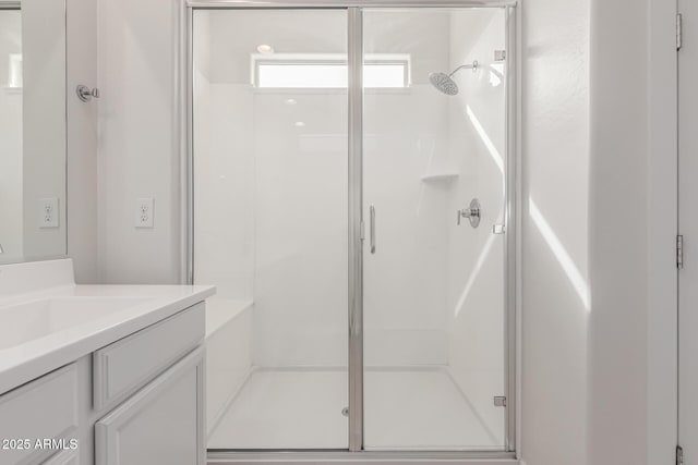 bathroom featuring a shower with shower door and vanity