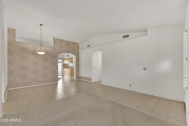 empty room with vaulted ceiling and light tile patterned floors