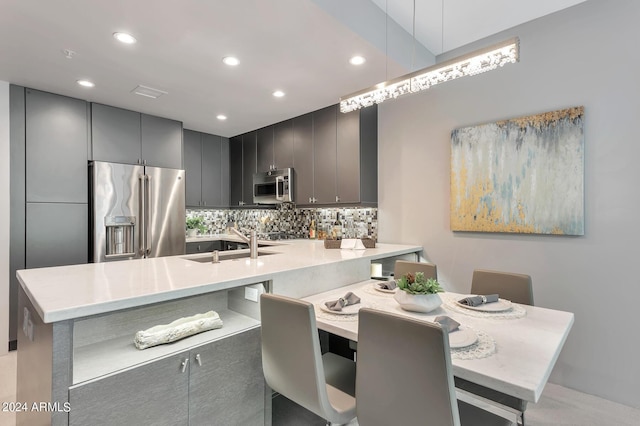 kitchen with a breakfast bar area, tasteful backsplash, kitchen peninsula, pendant lighting, and stainless steel appliances