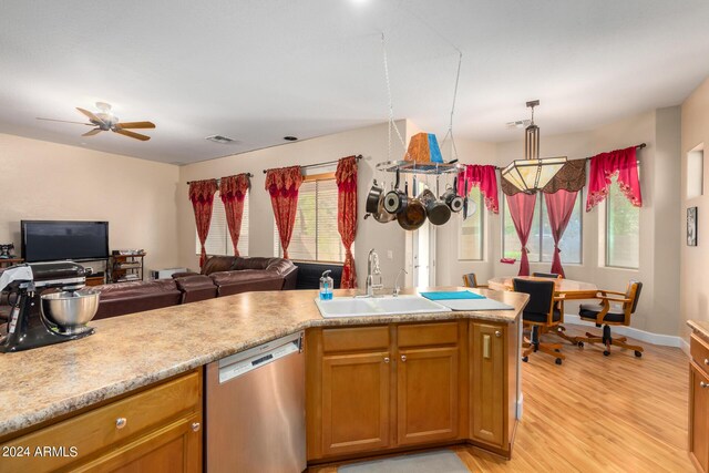 kitchen with a sink, open floor plan, light countertops, dishwasher, and light wood finished floors