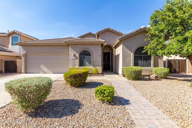 view of front facade with an attached garage, fence, concrete driveway, a tiled roof, and stucco siding