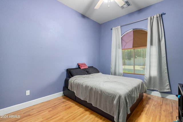 bedroom with lofted ceiling, visible vents, light wood-style flooring, ceiling fan, and baseboards