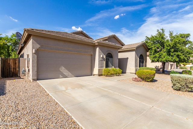 single story home with a garage, fence, concrete driveway, a tiled roof, and stucco siding