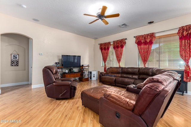 living room featuring arched walkways, a ceiling fan, visible vents, and light wood-style floors