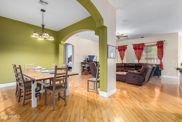 dining space with light wood-style floors, arched walkways, visible vents, and baseboards
