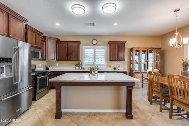 9952 W Jessie Ln, Peoria, AZ 85383 - kitchen with stainless steel appliances, light stone countertops, a chandelier, hanging light fixtures, and a center island
