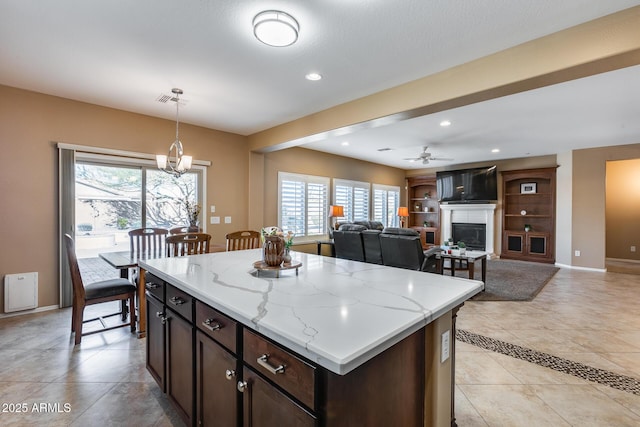 9952 W Jessie Ln, Peoria, AZ 85383 - kitchen with a glass covered fireplace, baseboards, pendant lighting, ceiling fan, and light stone countertops