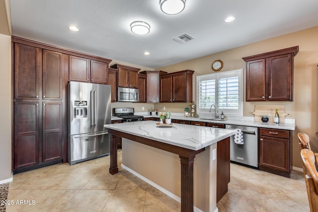 9952 W Jessie Ln, Peoria, AZ 85383 - kitchen featuring stainless steel appliances, a sink, a kitchen island, light stone counters, and light tile patterned floors