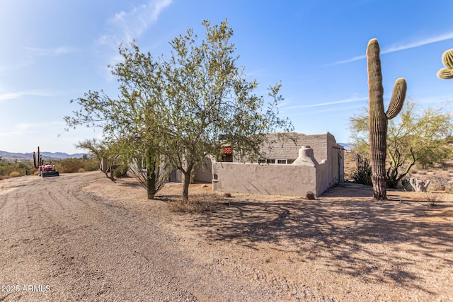 view of front facade with a fenced front yard, a mountain view, and stucco siding