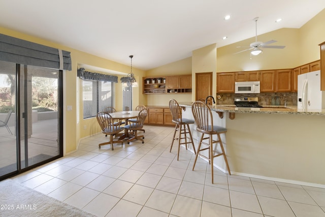 kitchen featuring decorative light fixtures, backsplash, light tile patterned floors, light stone counters, and white appliances