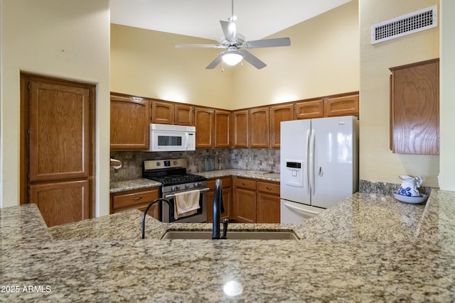 kitchen with sink, high vaulted ceiling, kitchen peninsula, white appliances, and backsplash