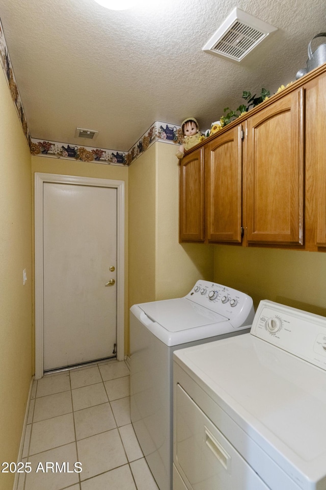 clothes washing area featuring independent washer and dryer, cabinets, light tile patterned flooring, and a textured ceiling