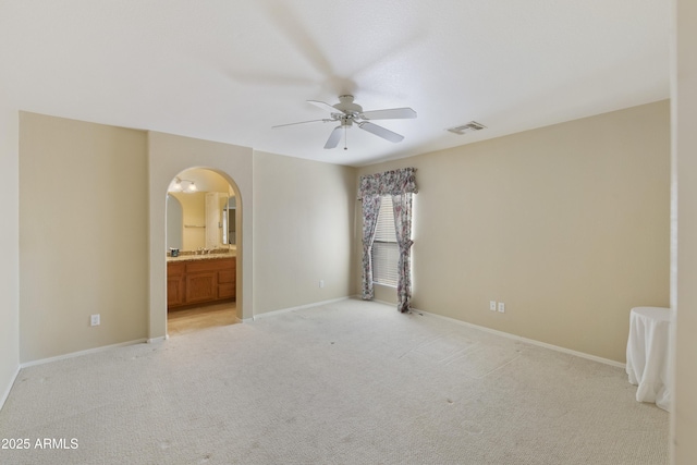 unfurnished bedroom with ensuite bathroom, light carpet, and ceiling fan