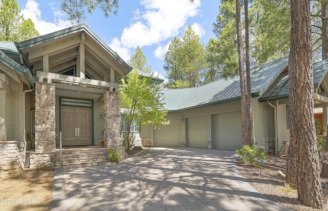 2036 Bessie Kidd Best, Flagstaff, AZ 86005 - entrance to property featuring a garage, concrete driveway, stone siding, and metal roof