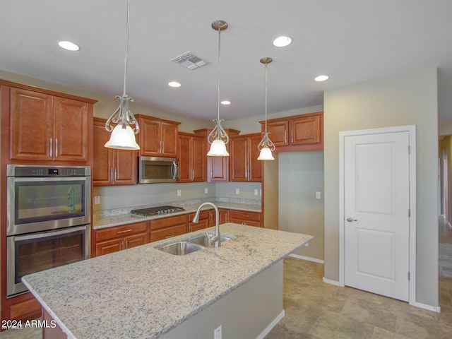 kitchen featuring appliances with stainless steel finishes, a center island with sink, hanging light fixtures, and sink