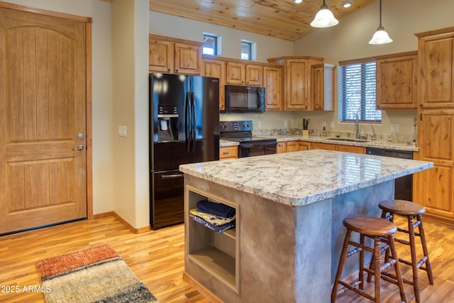 kitchen with sink, light stone counters, black appliances, a kitchen island, and wooden ceiling