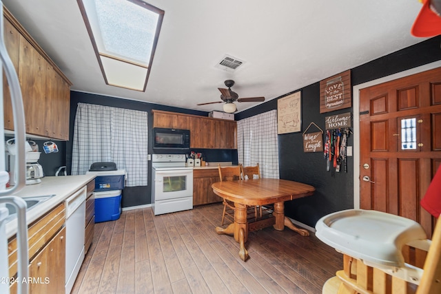 kitchen with ceiling fan, white appliances, dark hardwood / wood-style flooring, and a skylight