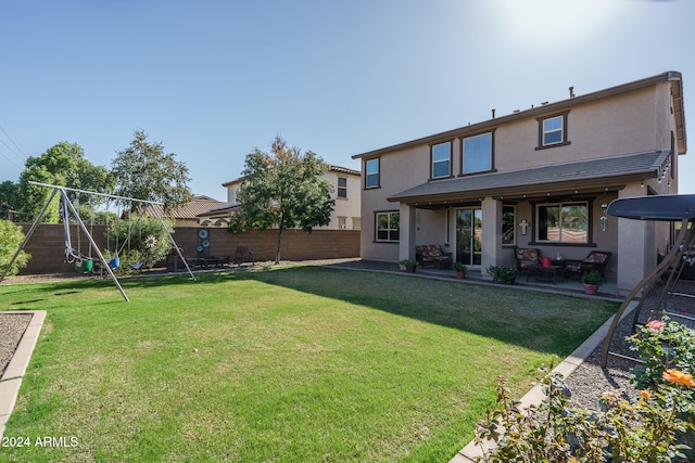 rear view of property featuring a playground, a patio area, and a yard