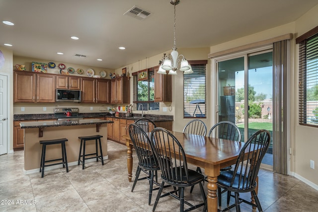 dining space with light tile patterned floors, an inviting chandelier, plenty of natural light, and sink