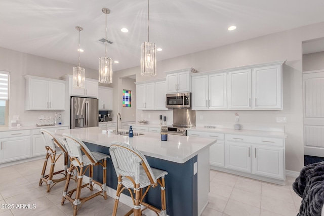 17896 W Amberwood Dr, Goodyear, AZ 85338 - kitchen with light tile patterned floors, a kitchen island with sink, visible vents, stainless steel appliances, and a sink
