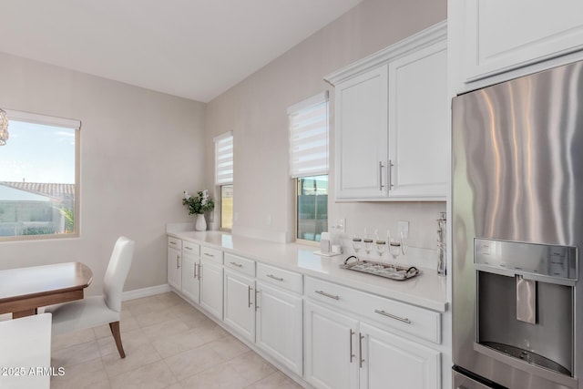 17896 W Amberwood Dr, Goodyear, AZ 85338 - kitchen featuring stainless steel fridge with ice dispenser, baseboards, light countertops, light tile patterned flooring, and white cabinets