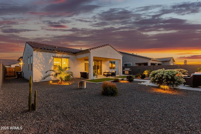 17896 W Amberwood Dr, Goodyear, AZ 85338 - back of property at dusk with a patio area, stucco siding, fence, and a tile roof