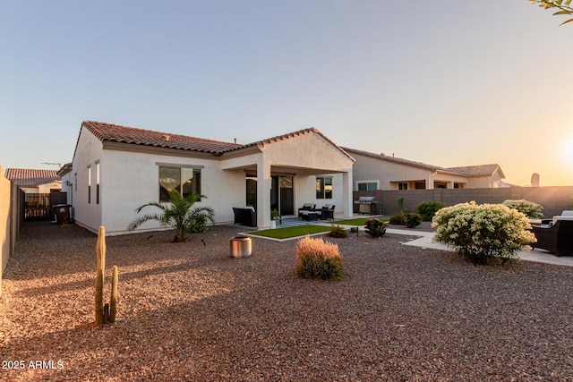 17896 W Amberwood Dr, Goodyear, AZ 85338 - back of house at dusk with a patio area, stucco siding, a fenced backyard, and a tile roof