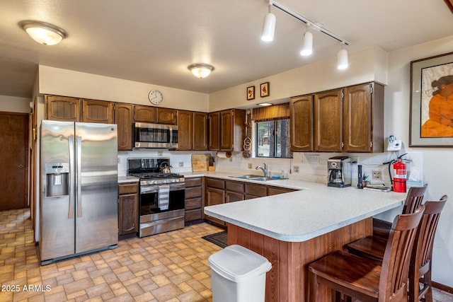 kitchen with light countertops, a sink, a breakfast bar area, a peninsula, and stainless steel appliances