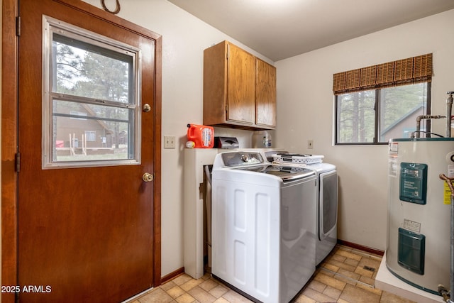 laundry area featuring electric water heater, baseboards, washing machine and clothes dryer, stone tile flooring, and cabinet space