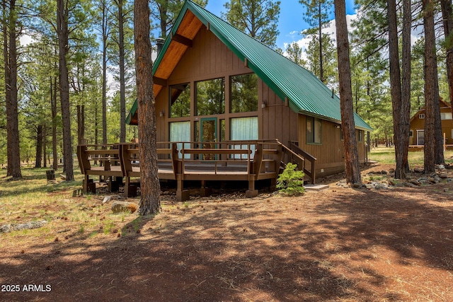rear view of property with metal roof, a standing seam roof, and a wooden deck