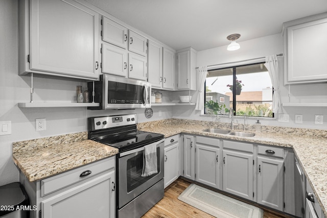 1408 N 62nd Pl, Mesa, AZ 85205 - kitchen featuring appliances with stainless steel finishes, a sink, open shelves, light wood-type flooring, and light stone countertops