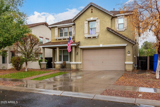 traditional-style home with fence, a tiled roof, stucco siding, driveway, and a garage