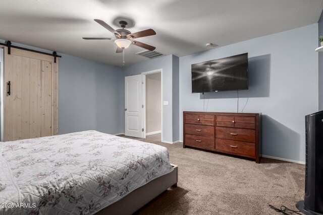 carpeted bedroom with a barn door, visible vents, a ceiling fan, and baseboards