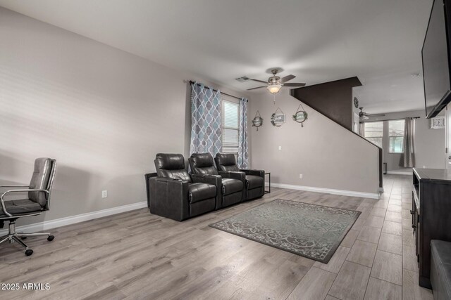 living room featuring plenty of natural light, a ceiling fan, baseboards, and wood finished floors