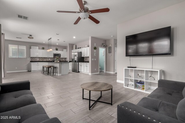 living area with recessed lighting, visible vents, a ceiling fan, light wood-style floors, and baseboards