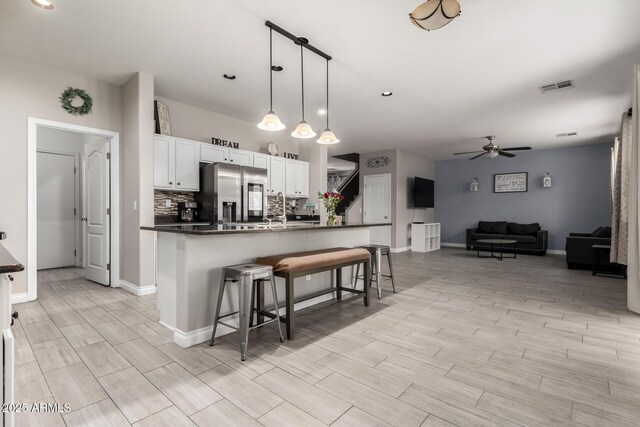 kitchen featuring dark countertops, wood tiled floor, stainless steel fridge, ceiling fan, and visible vents