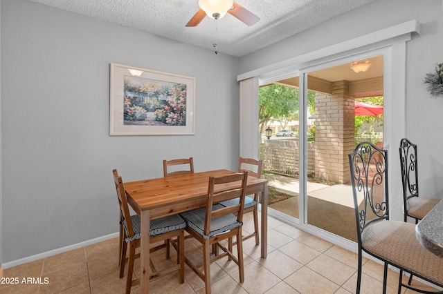 dining area with a textured ceiling, a ceiling fan, baseboards, and light tile patterned floors