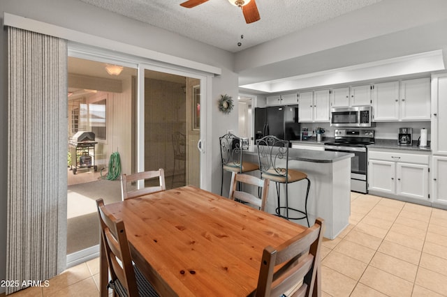 dining area with a ceiling fan, a textured ceiling, and light tile patterned floors