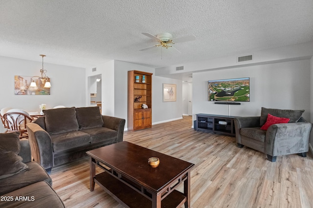 living area featuring ceiling fan with notable chandelier, visible vents, and light wood-style floors