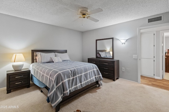 bedroom featuring a textured ceiling, baseboards, visible vents, and light colored carpet