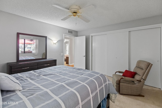 bedroom featuring visible vents, a ceiling fan, carpet floors, a closet, and a textured ceiling