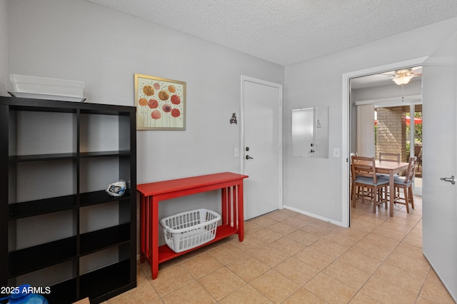 foyer entrance featuring baseboards, a ceiling fan, a textured ceiling, and light tile patterned floors