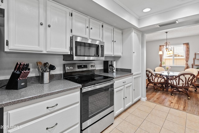 kitchen with a chandelier, light tile patterned flooring, white cabinetry, and stainless steel appliances
