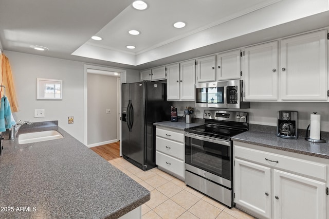 kitchen with a sink, dark countertops, appliances with stainless steel finishes, crown molding, and light tile patterned floors