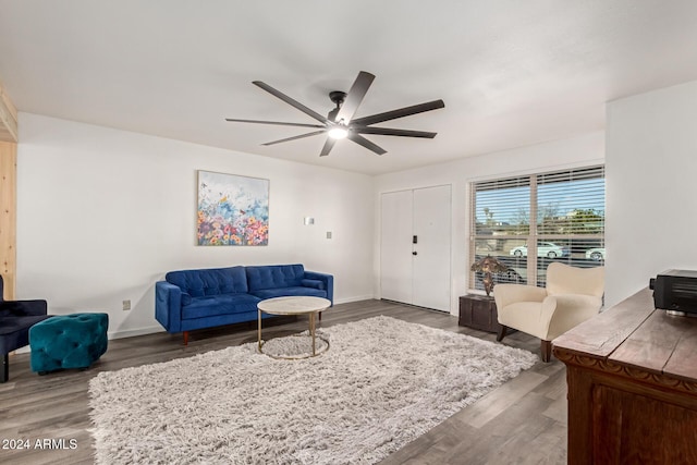 living area featuring baseboards, a ceiling fan, and wood finished floors